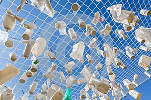 Plastic containers in fishing net against blue sky - concept of water pollution, environmental issue