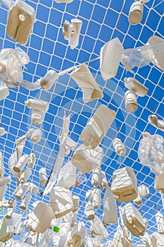 Plastic containers in fishing net against blue sky - concept of water pollution, environmental issue