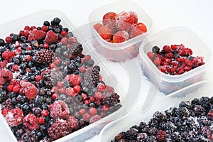Plastic containers of frozen mixed berries in snow