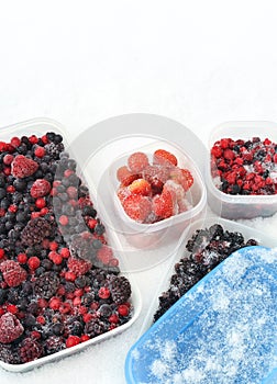 Plastic containers of frozen mixed berries in snow