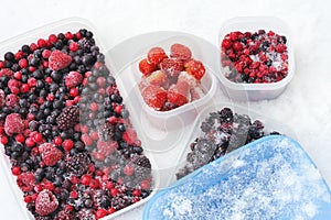 Plastic containers of frozen mixed berries in snow photo