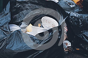 Plastic cup and foam bowl in black garbage bags