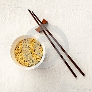 Plastic cup of instant ramen noodles, overhead square shot with chopsticks
