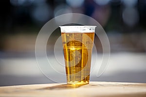 Plastic cup of light beer standing on the table