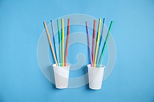 Plastic cups and colorful drinking straws on blue background