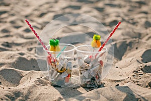 Plastic cups with straw and tropical decor and Garbage on the beach, trash, plastic, bottle, foam, rubbish, sigarette stub. photo