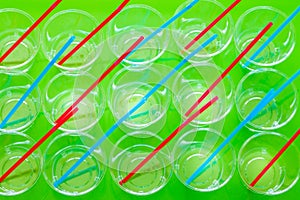 Plastic disposable cups with colored straws, Concept of reducing the amount of artificial materials on earth / green background