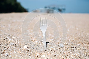 Plastic disposable fork stick out of sea beach sand