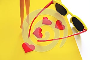 Plastic doll girl`s legs , hearts and sunglasses, travel and beauty concept. Minimal funny and quirky design still life