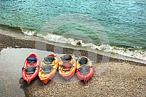 Plastic double kayaks lie on the seashore