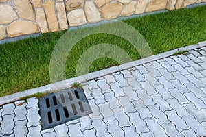 Plastic drain gutter, green grass lawn and stone pavement sidewalk