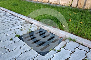 Plastic drain gutter, green grass lawn and stone pavement sidewalk