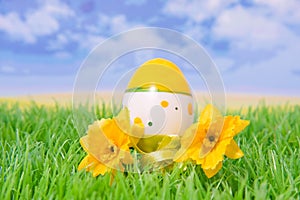 Plastic easter egg on grass with flowers