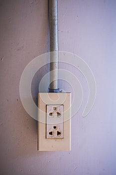 Plastic electric plug on concrete wall with steel tube