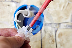 Plastic electrical connector or terminal blocks, an electrician tightens mounting screw holding an electrical wire when