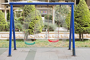 Plastic and Empty red and green chain swings in children playground. chain swings hanging in garden . Childs swing in a park