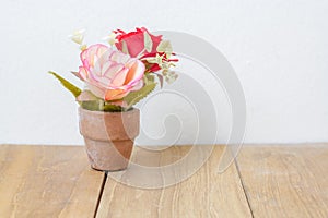 Plastic flower in pot on wooden board