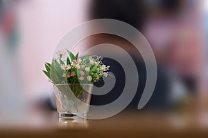 Plastic flowers in clear vase on table on blur background