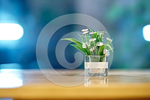 Plastic flowers in vase on table on bokeh background