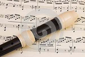 Plastic flute recorder over a music score sheet