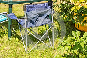 Plastic folding table and folding chairs for camping stand on the grass on a Sunny summer day