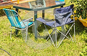 Plastic folding table and folding chairs for camping stand on the grass on a Sunny summer day