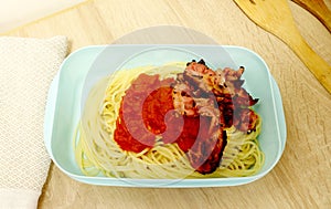 Plastic food container packed with spaghetti, tomato sauce and bacon