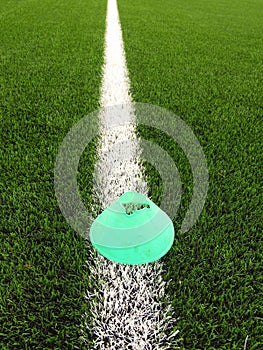 Plastic football green turf playground with grinded black rubber in core and bright green blue plastic cone. White line marks