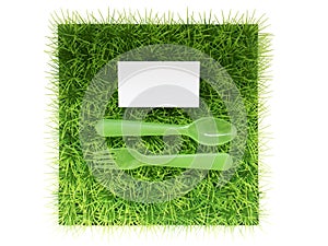 Plastic fork and spoon on green grass , space for text