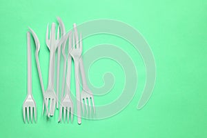 Plastic forks on a green background with a copy of the space. Disposable food appliances