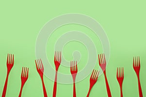 Plastic forks on green background, flat lay. Space for text