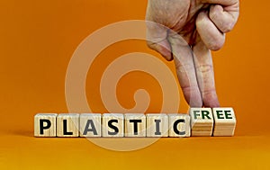 Plastic free symbol. Male hand turns cubes with words `plastic free`. Beautiful orange background. Business, ecological end