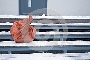 a plastic garbage bag abandoned outside a house, winter scene