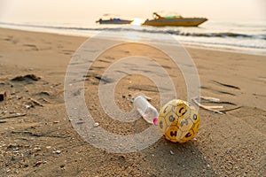 Plastic garbage on a beach with boats on background