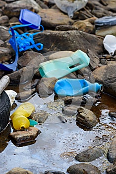 Plastic garbage and old tire in oily dirty water