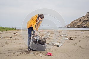 Plastic garbage. Sea and ocean pollution. Beach clean up. Young man picking used plastic bottles on sand shore