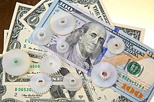 Plastic gears on the background of dollars. The concept of interaction in business to achieve financial success