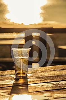 Plastic glass which has beer inside on wooden table