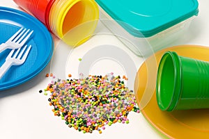Plastic granules and disposable tableware made of polyethylene, polypropylene polymeric material on a white background. BPA FREE