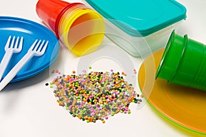 Plastic granules and disposable tableware made of polyethylene, polypropylene polymeric material on a white background. BPA FREE