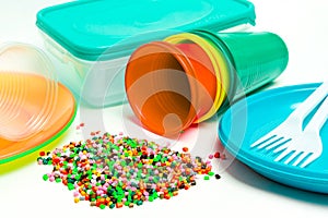 Plastic granules and disposable tableware made of polyethylene, polypropylene polymeric material on a white background. BPA FREE