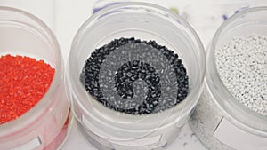 Plastic granules on extruder for making plastics on extrusion manufactory - red, black and white