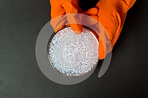 Plastic granules . Polyethylene pellets and hands with orange gloves. Quality control of plastic in the laboratory in production.