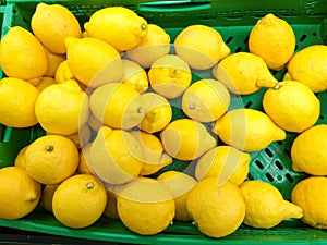 plastic green box at the market plenty of heap yellow lemons ready to be sold to customers