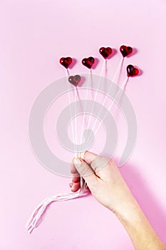 Plastic hearts on a pink background as a cluster of ballon, holding by a woman`s hand.