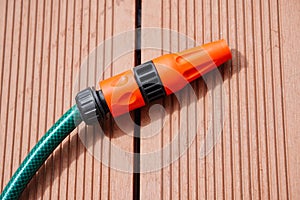 a plastic hose being used on the deck, connected to the side of a wooden