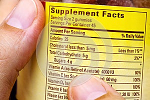 Plastic jar with supplement facts of multivitamins in woman hand