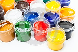 Plastic jars of colored paints on white background