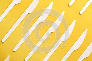 Plastic knives on color background, top view