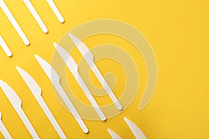 Plastic knives on color background, top view with space for text